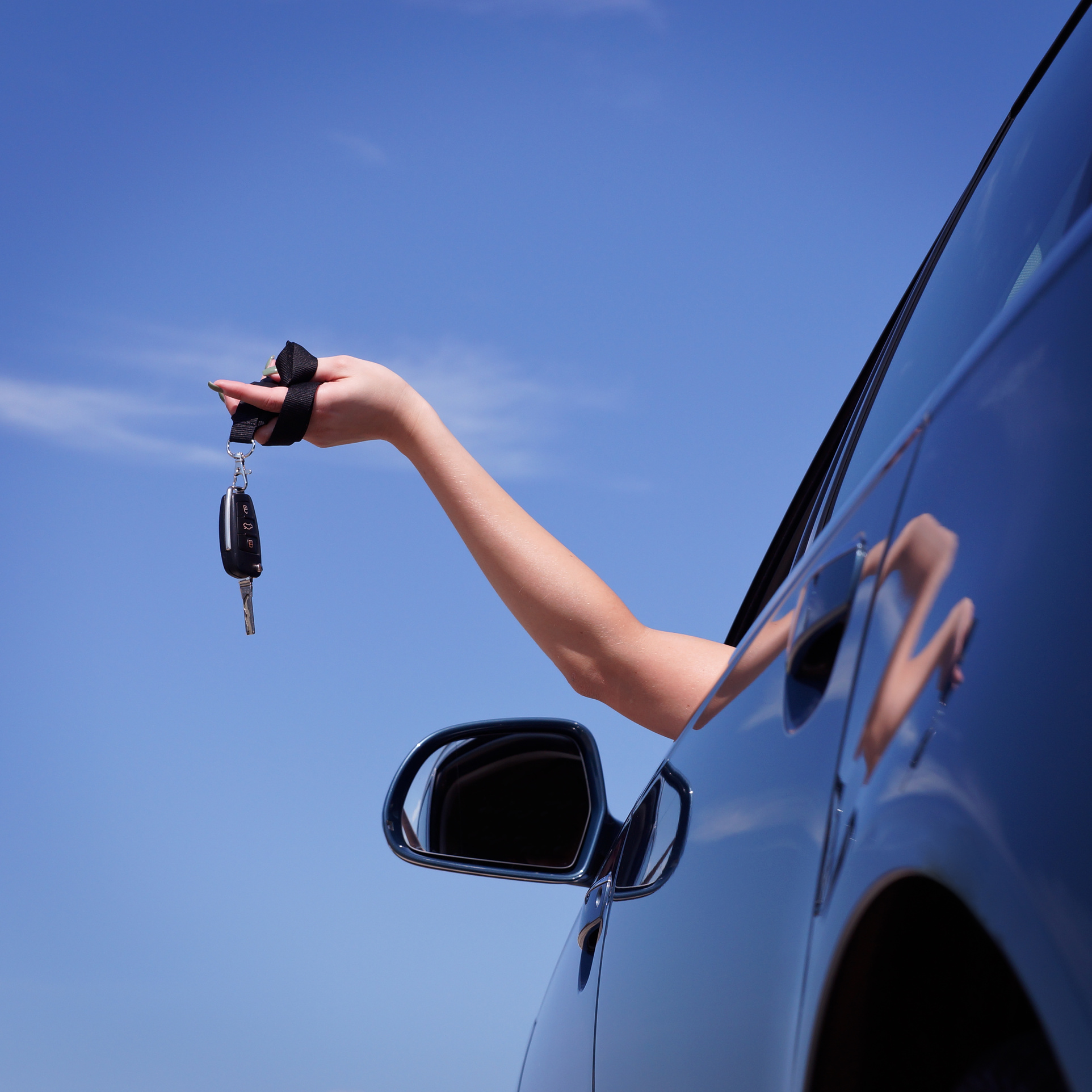 Frau hält Schlüssel aus dem Autofenster